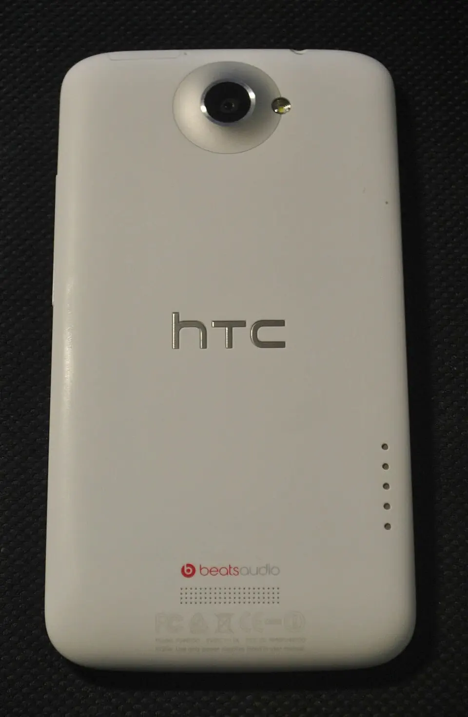 白色 HTC One X 实物背面，显示凸起相机与背部触点
