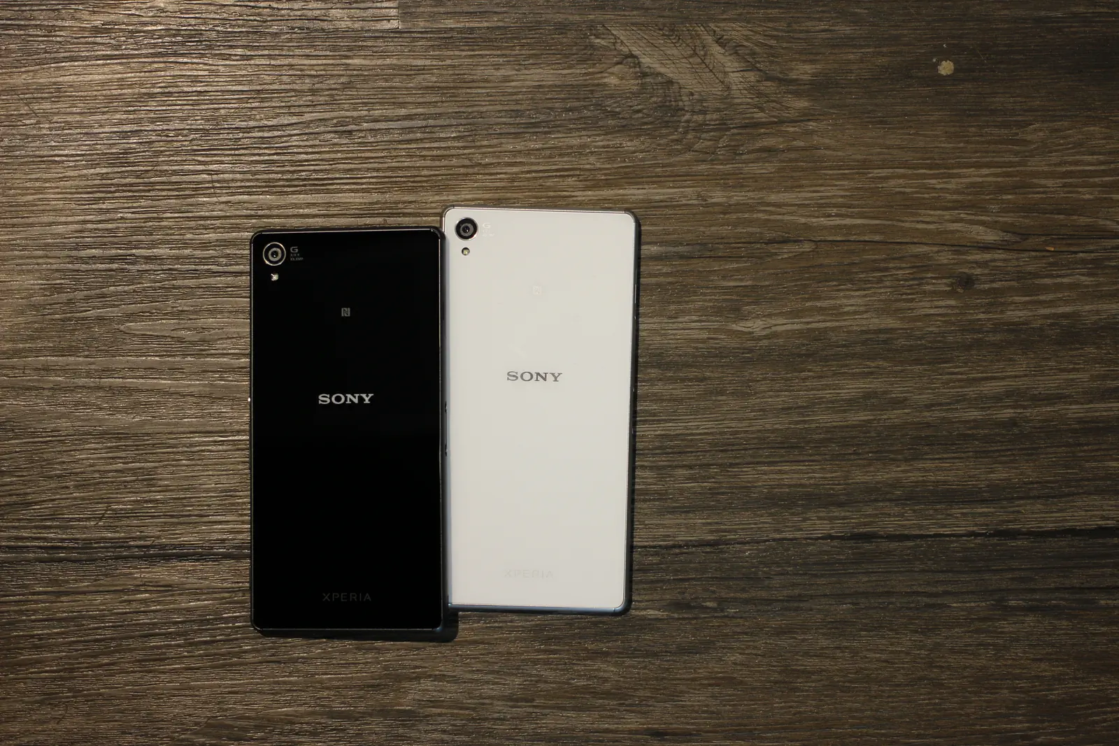 Black and white Sony Xperia Z3 handsets in the original rear photograph, both devices and wooden background retained