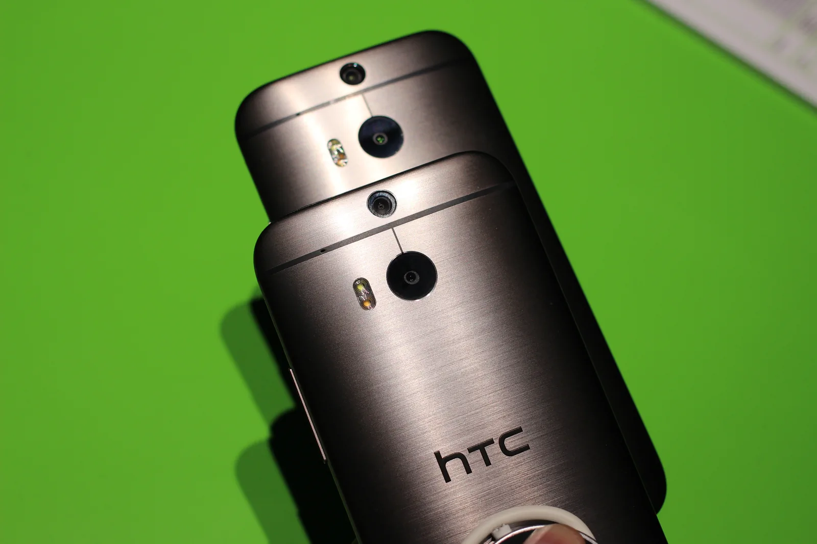 两部 HTC One（M8）实机的 Duo 后摄结构特写，原图保留持机手指
