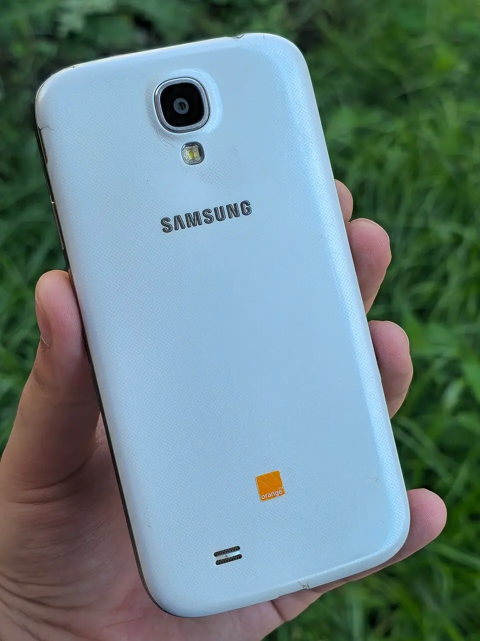 White Frost Samsung Galaxy S4 rear with Orange branding; the photograph does not establish its radio variant